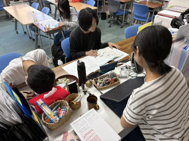 職員の机をかこんで、教科書を広げて学ぶ生徒たち